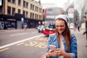 happy woman walking in london checking app