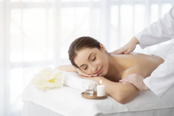 Spa Massage. Indian Woman Relaxing On Table While Therapist Massaging Her Shoulders