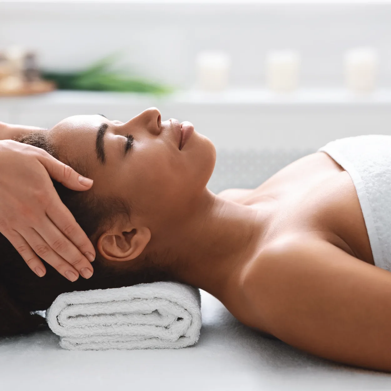 Young black woman getting head massage from massage therapist