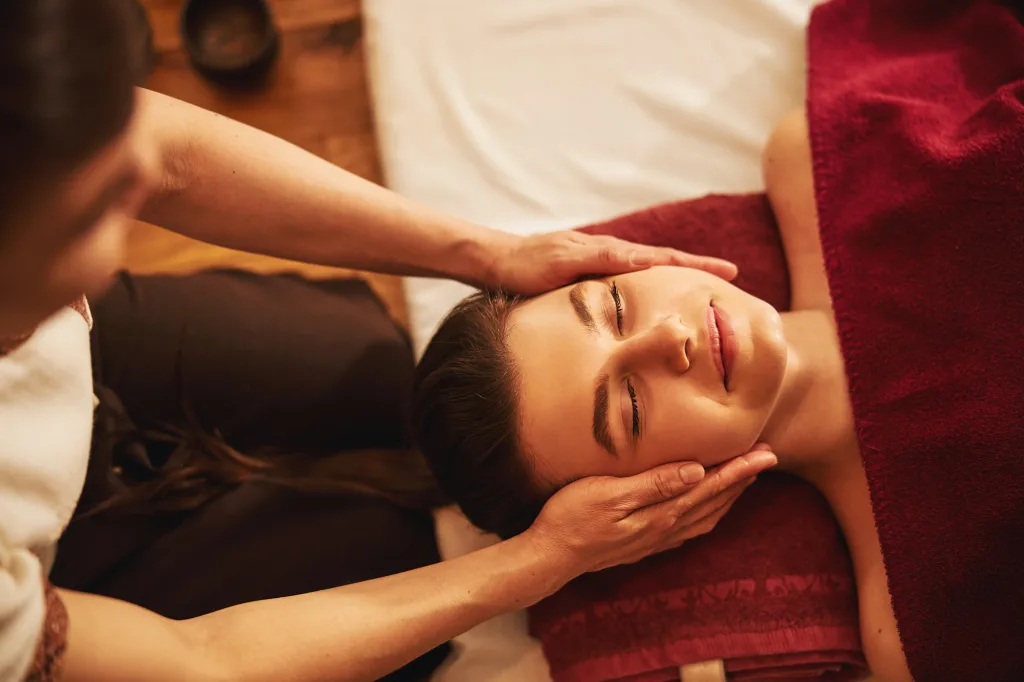 Face of satisfied lady receiving massage of cheeks