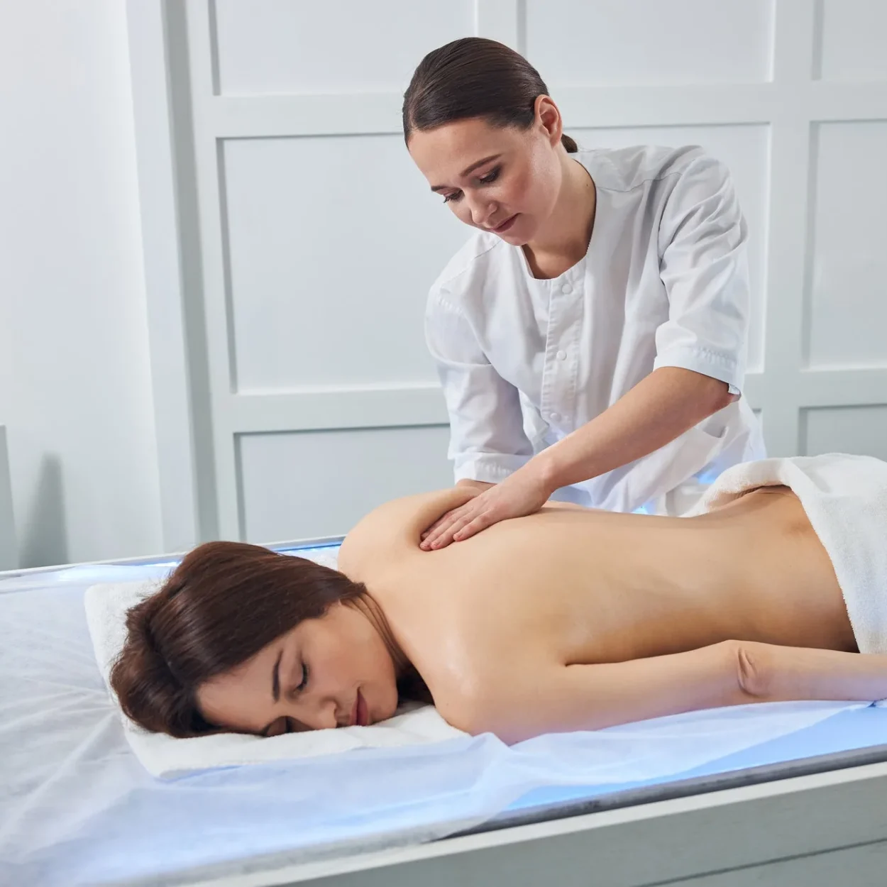 Masseuse kneading the shoulder skin with her palm